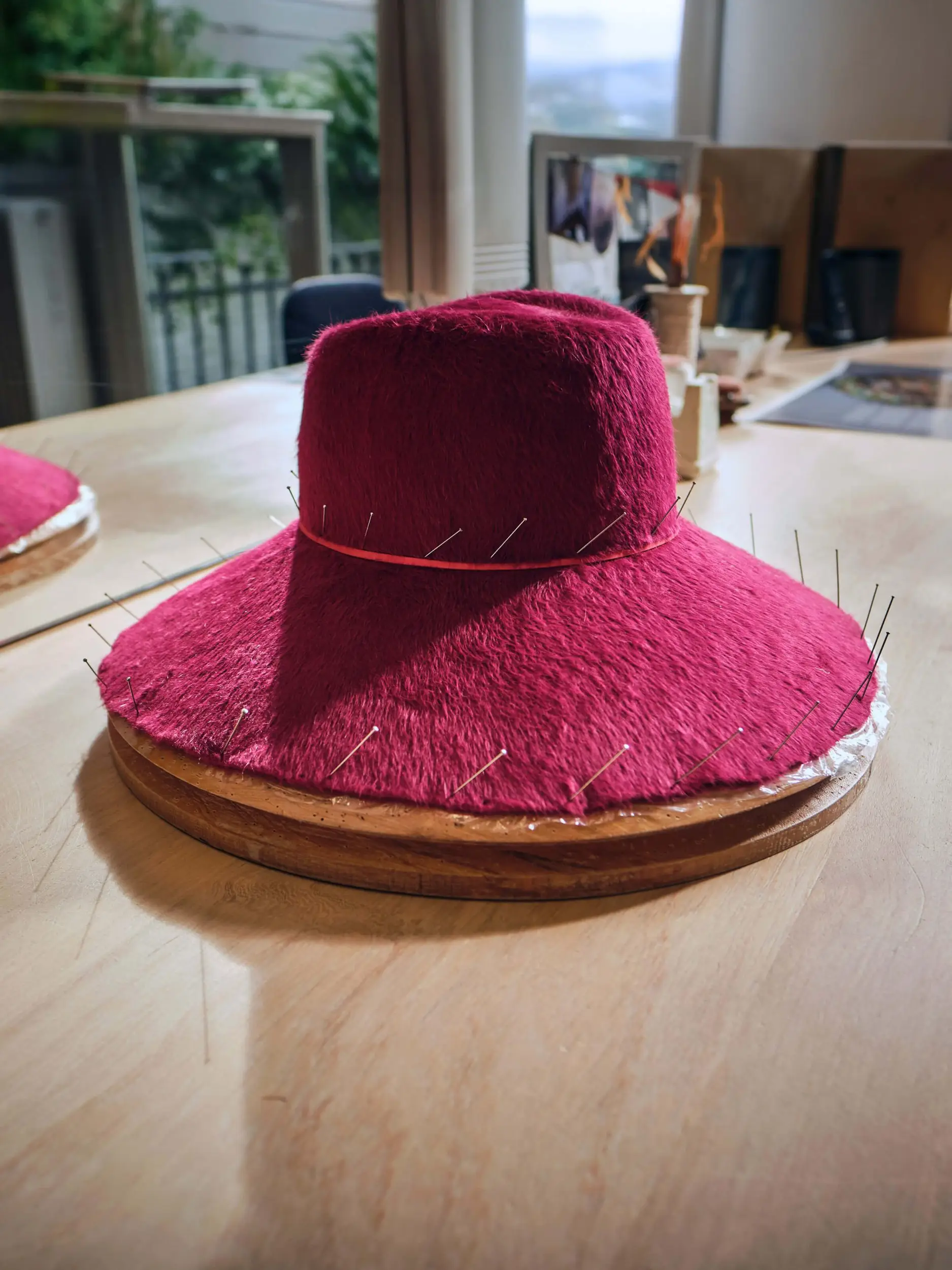 pink felt hat blocked on a wooden block