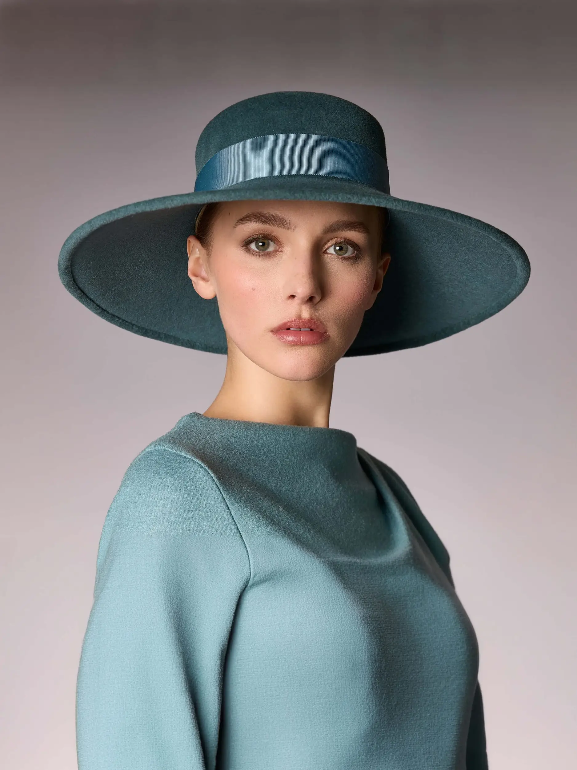 Woman wearing the green duck-shaped winter capeline hat of Hepburn