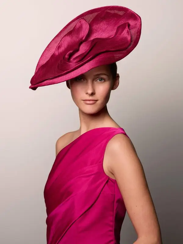 Vrouw draagt de Libeline framboze-fascinator van banenvezel in combinatie met haar jurk