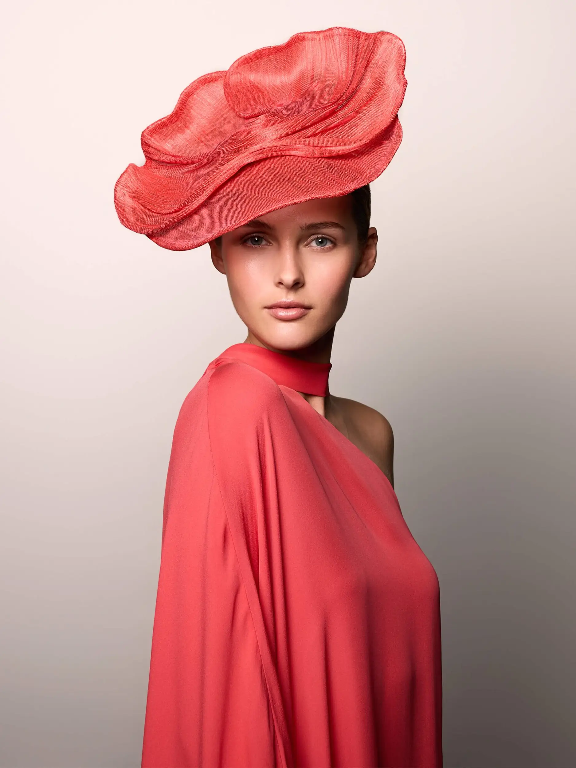 Woman wearing the exceptional Nenufy wedding hat made of banana fiber paired with an orange mandarin dress