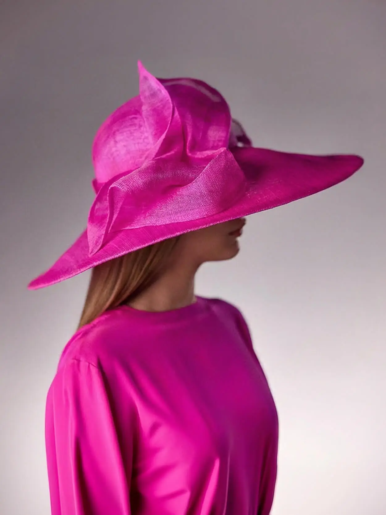 Woman wearing the Fuchsia pink Abelia cloche hat made of banana fibre