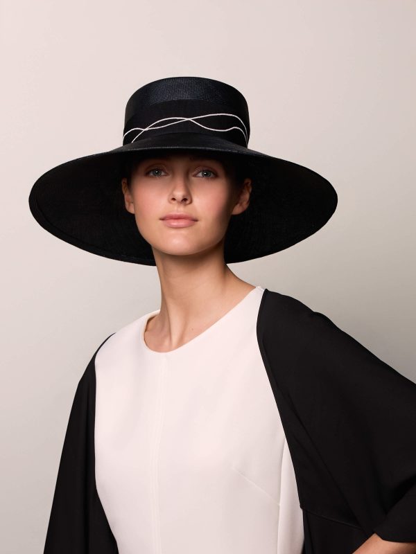 Woman wearing a black boater hat and a black stole.