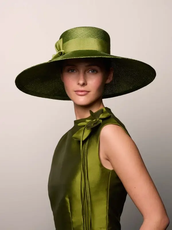 Woman wearing the Arakis capeline hat and a green straw panama hat and a matching dress
