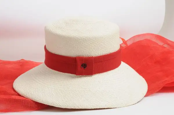 Close-up of a Fraline cloche hat, boater hat with a red ribbon