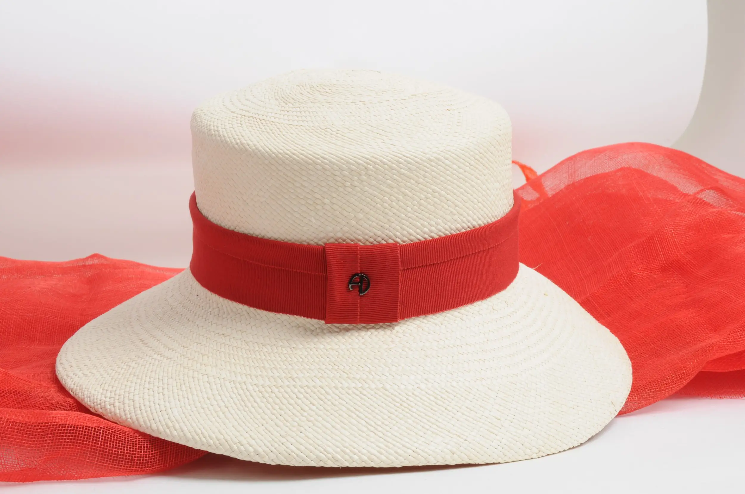 Close-up of a Fraline cloche hat, boater hat with a red ribbon