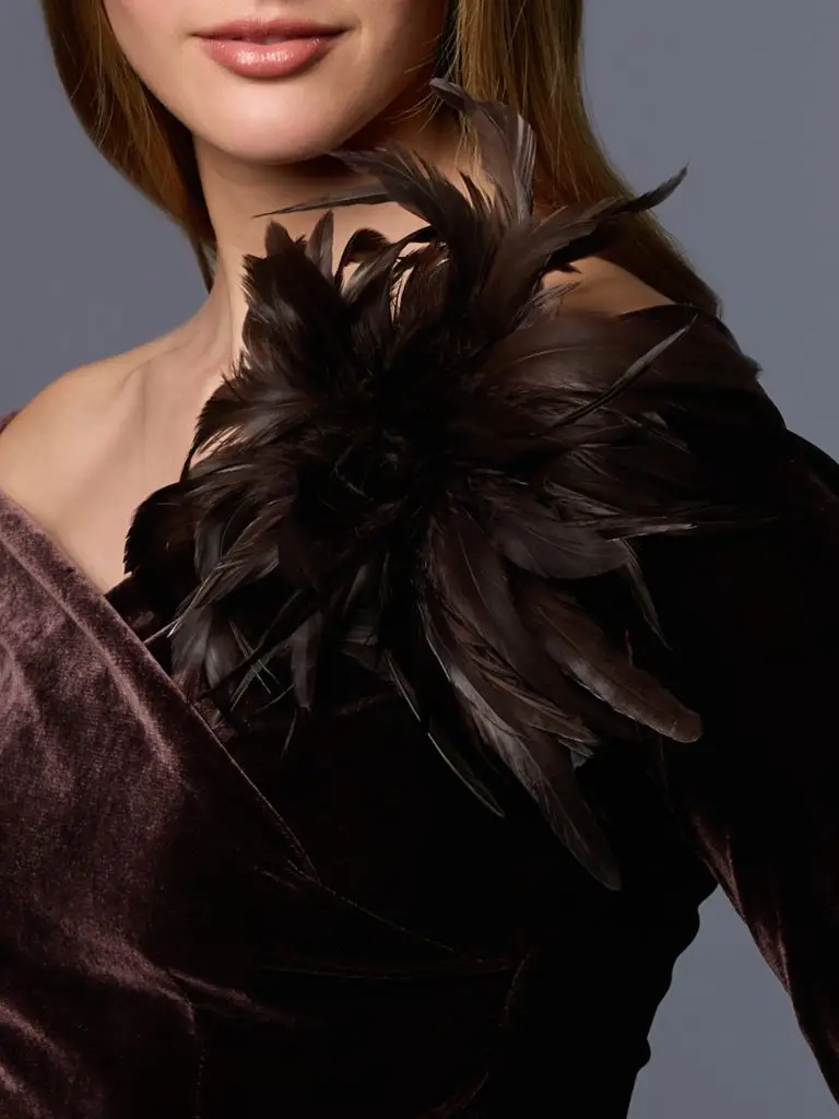 Woman wearing the accessory brooch adorned with green feathers