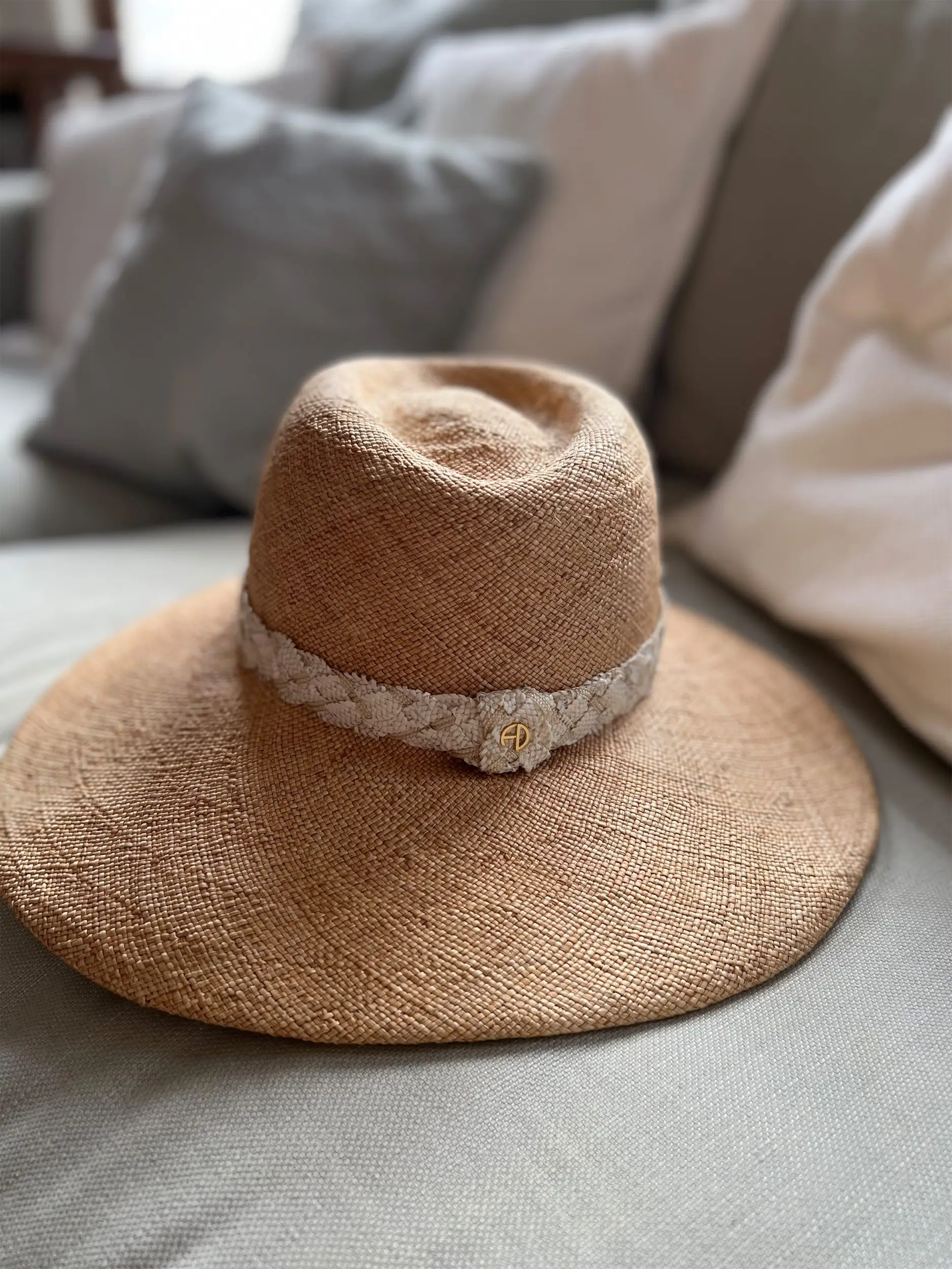 Beige straw hat on a sofa – Emilia PS – Maison Fabienne Delvigne