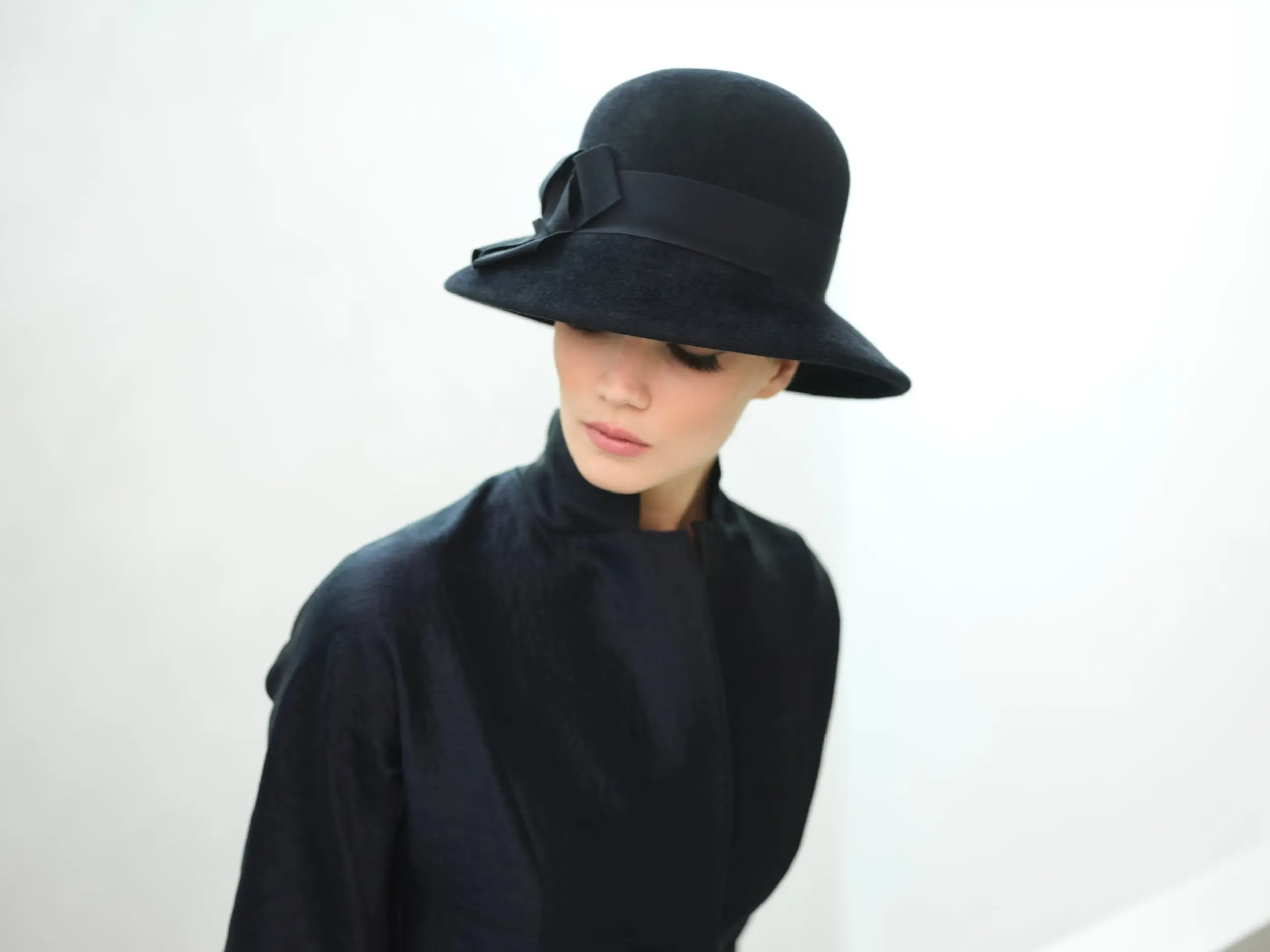 woman with head bowed wearing a felt cloche hat
