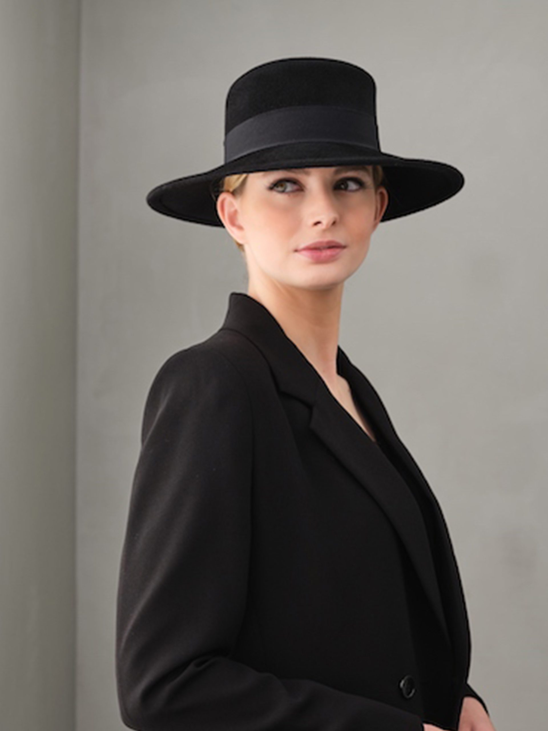 Woman wearing a black velvet felt boater hat matching her clothes