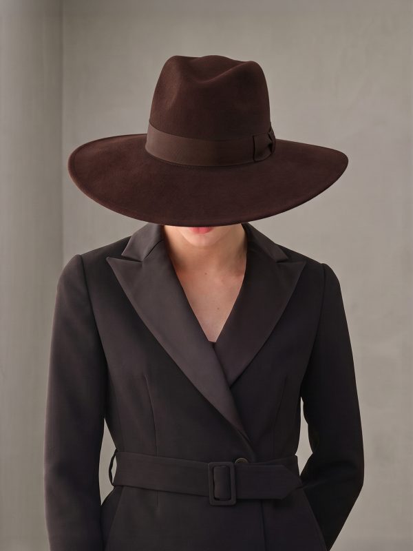 Woman with her head bowed wearing the Felicia brown felt fedora hat by Maison Fabienne Delvigne1