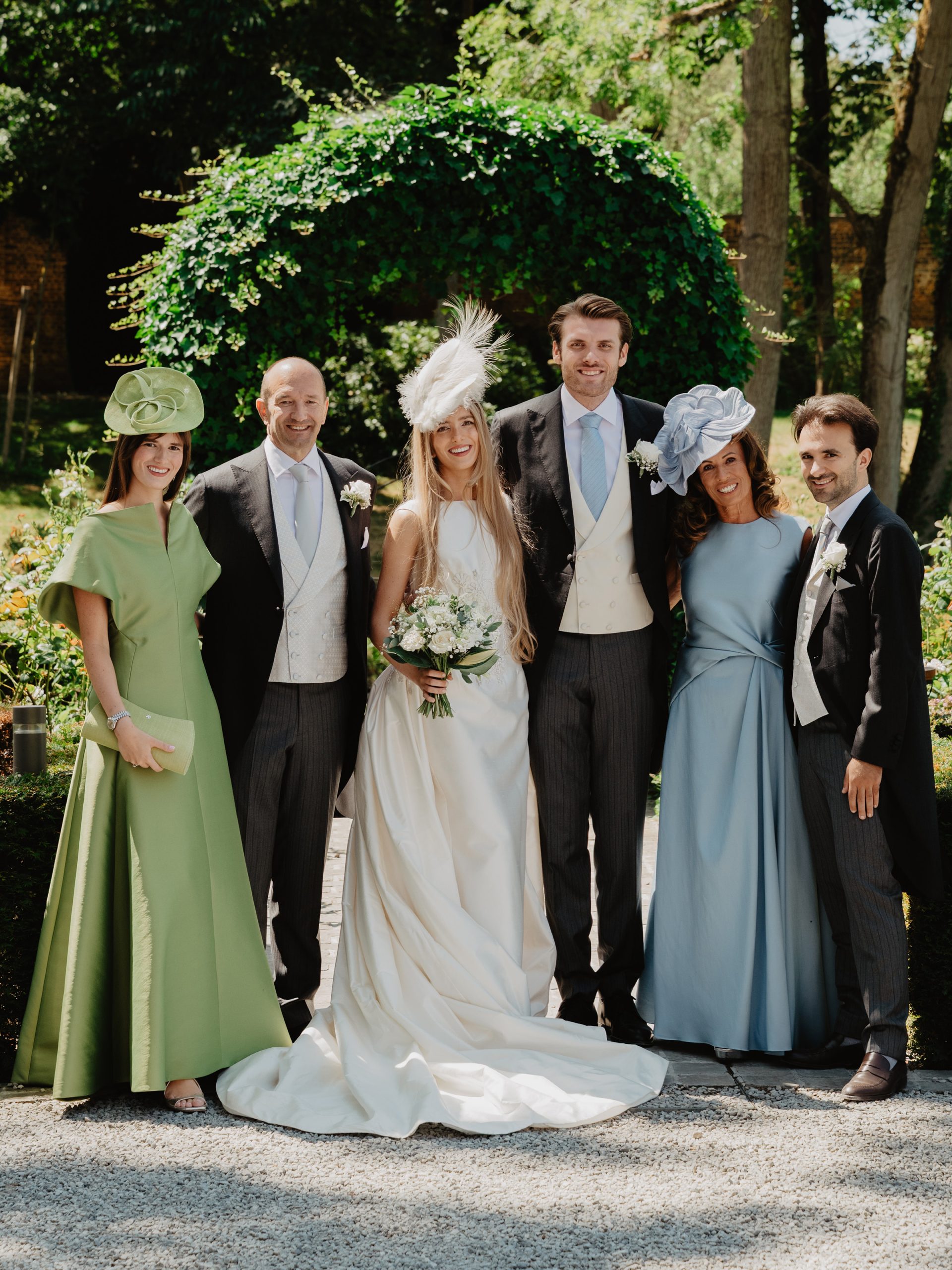 Family around the married couple. The women all wear colorful hats by Maison Fabienne Delvigne
